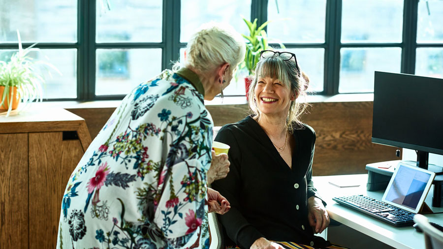 Why Josh Lamb recommends NS&I - the image is of two ladies talking and smiling, the lady facing the camera has her glasses perched stylishly on the top of her hair